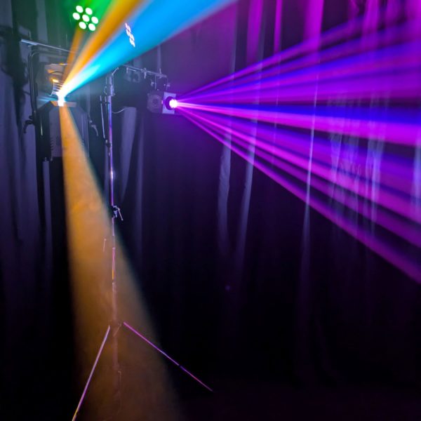 Hire dancefloor lights kit: pictured on a stand generating multi-coloured beam effects across a haze filled room.